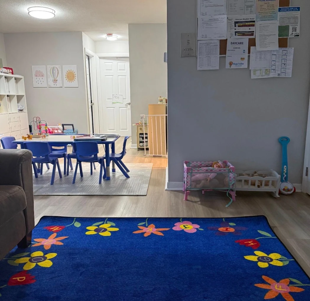 Bright child care room with learning tables, small chairs, a play rug and toys
