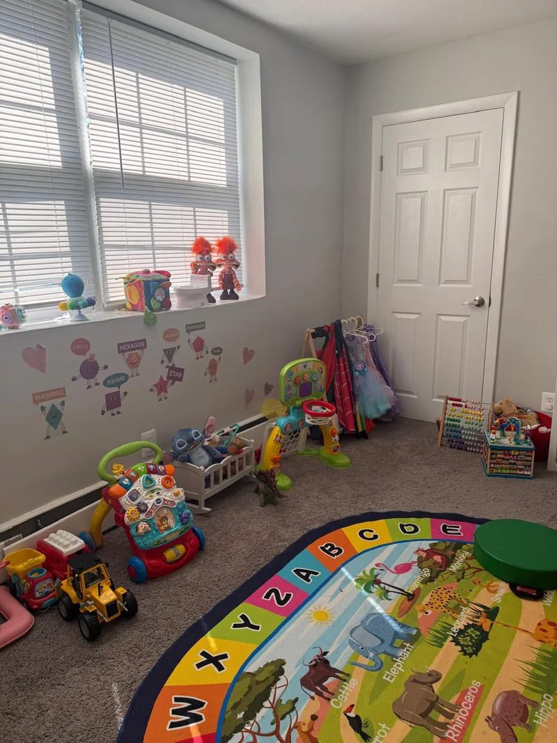 Toys and a colorful alphabet rug beside the window in the daycare